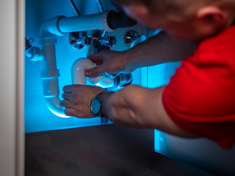 Plomero reparando las tuberías debajo de un lavabo
