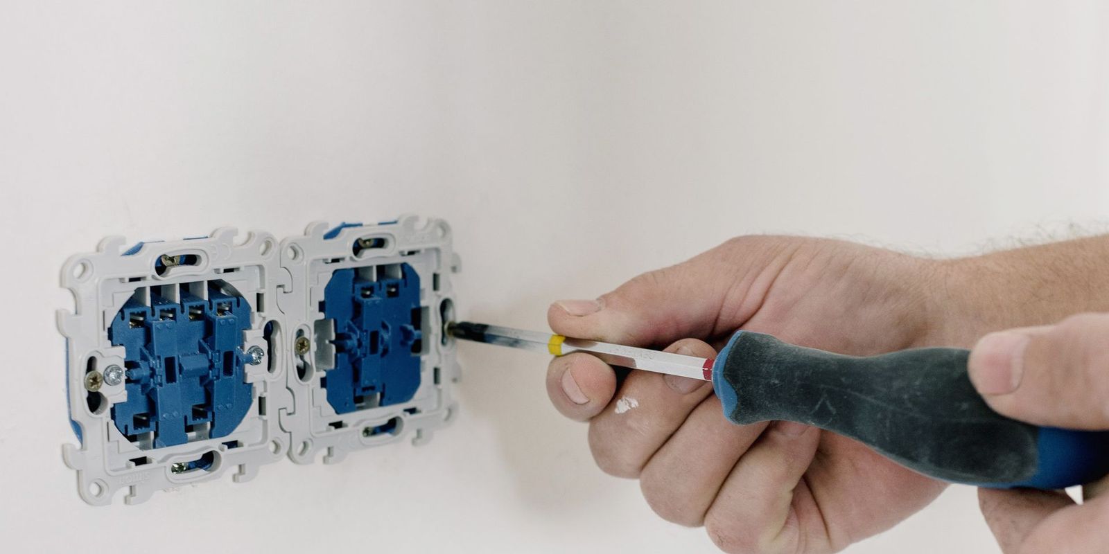 Manos de un electricista instalando contactos en una pared de casa